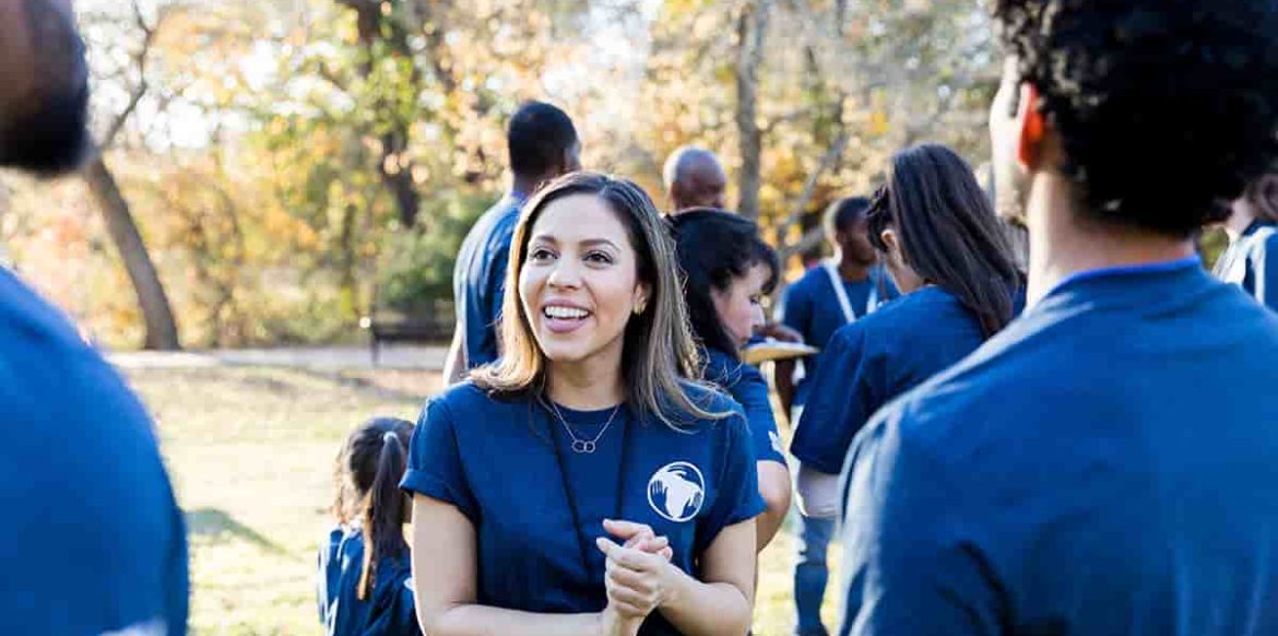 Mid adult Hispanic woman volunteers with her friends during community cleanup day.